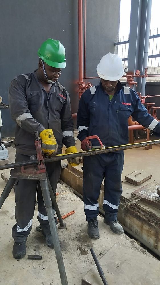 Two Fixpro technicians measuring and cutting pipe during fabrication