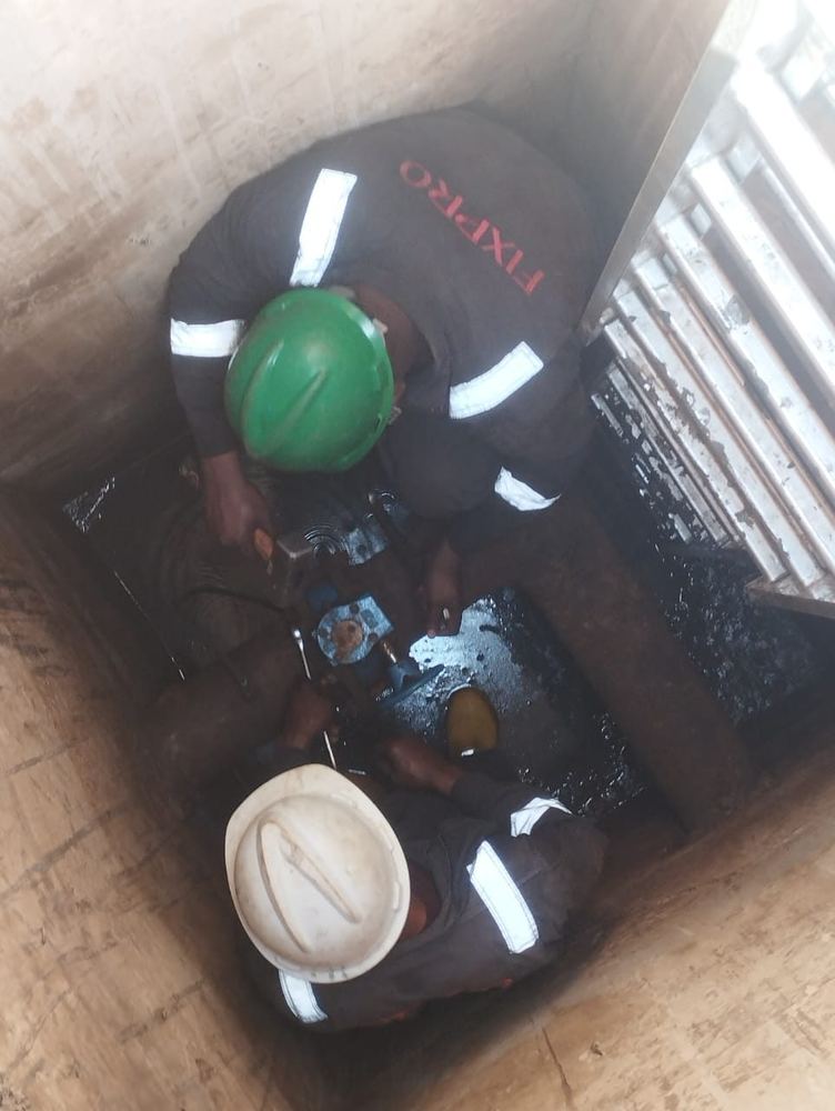 Technicians replacing a valve inside a tank access chamber