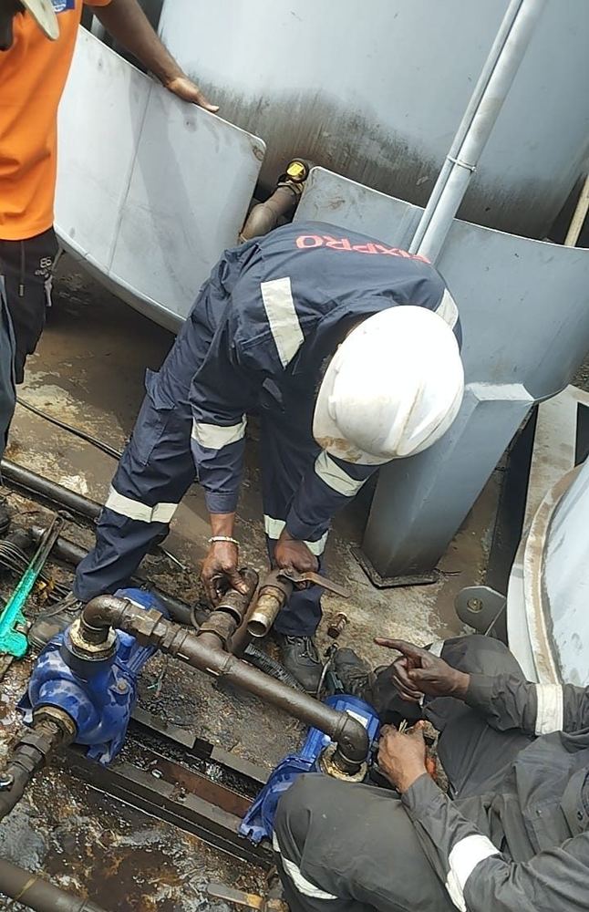 Technicians installing transfer pumps and associated pipework beside bulk tanks